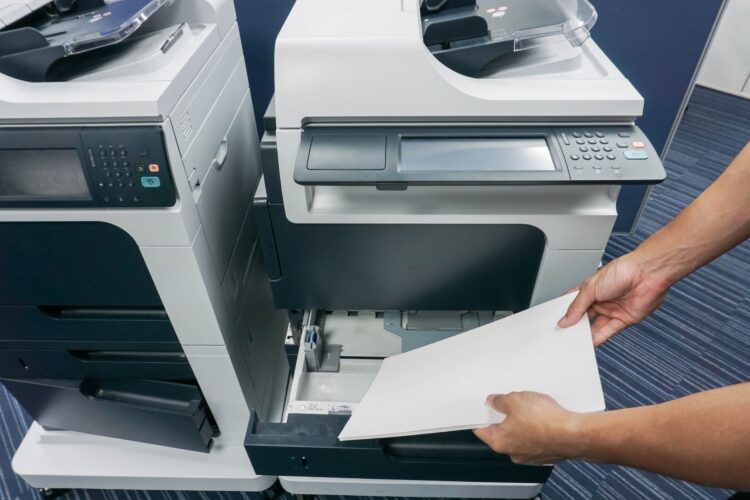 man putting paper sheet into printer tray